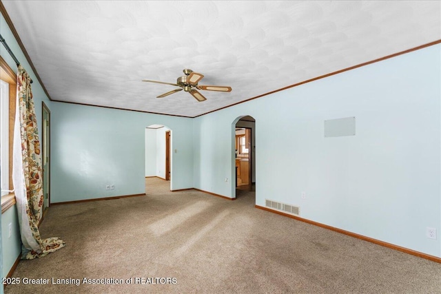 empty room featuring light carpet, crown molding, and ceiling fan