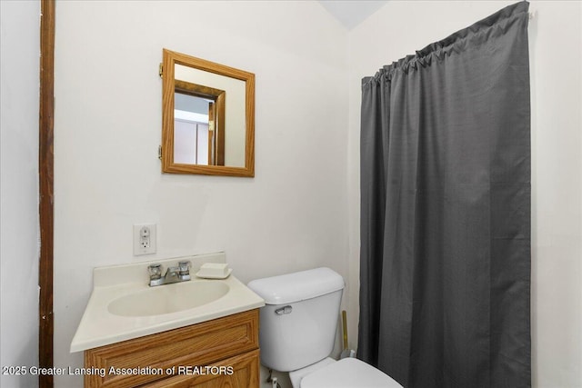 bathroom with lofted ceiling, vanity, and toilet