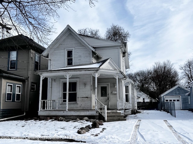 view of front of property with a garage, a porch, and an outbuilding