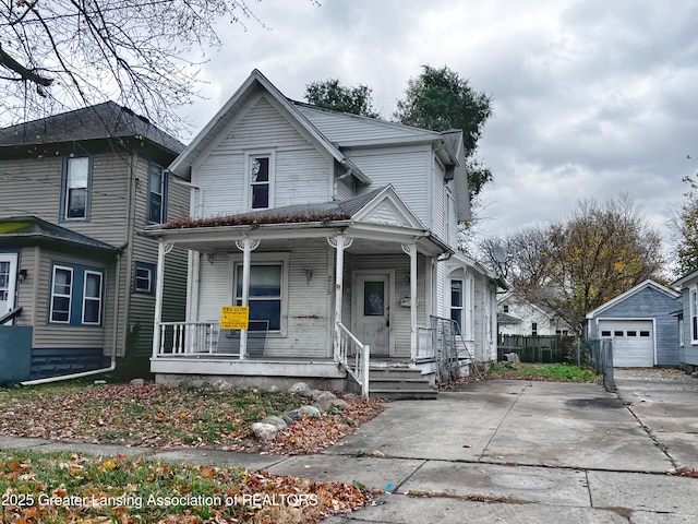 215 N Pleasant St, Jackson, MI 49202 - view of front facade with covered porch, an outdoor structure, driveway, and a detached garage