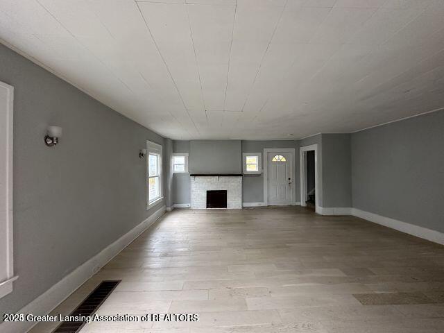 unfurnished living room featuring a stone fireplace and light hardwood / wood-style flooring