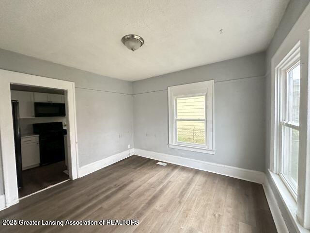 unfurnished room featuring dark wood-type flooring and a textured ceiling