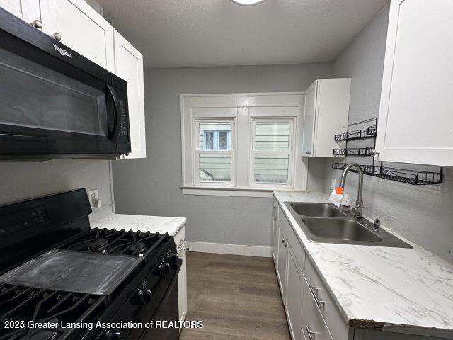 kitchen featuring white cabinetry, sink, and black appliances