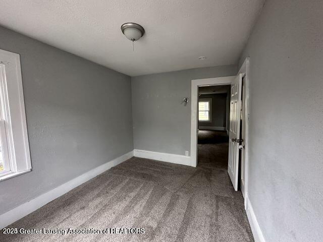 carpeted empty room with a textured ceiling