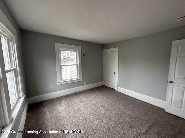 unfurnished room featuring dark colored carpet and a wealth of natural light