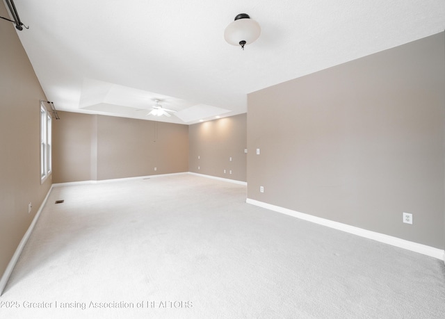 carpeted empty room featuring a raised ceiling and ceiling fan