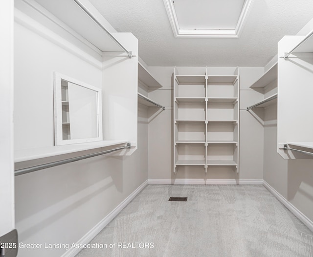 walk in closet featuring light colored carpet