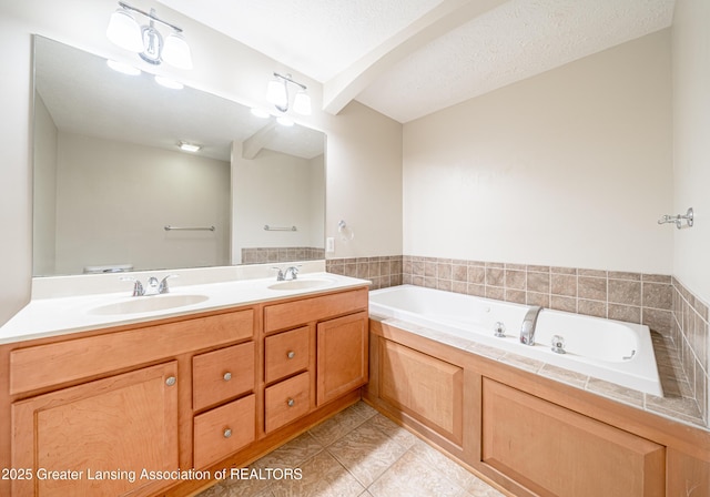 bathroom with tile patterned floors, a tub to relax in, vanity, and a textured ceiling