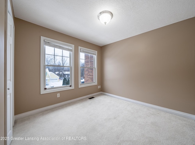 carpeted spare room with a textured ceiling