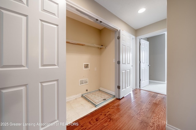 clothes washing area with washer hookup and light hardwood / wood-style flooring