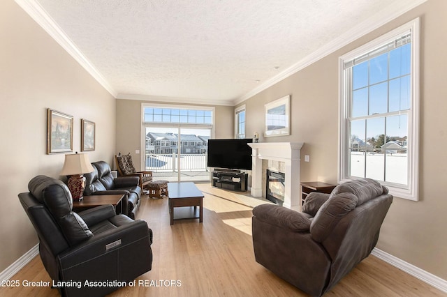 living room featuring a high end fireplace, ornamental molding, a textured ceiling, and light wood-type flooring