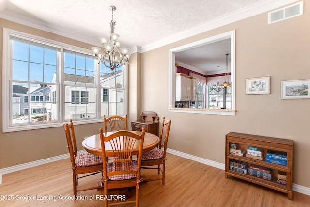 dining space with crown molding, light hardwood / wood-style flooring, a textured ceiling, and a chandelier