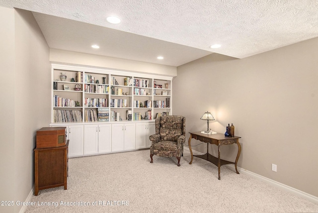 living area featuring light carpet and a textured ceiling