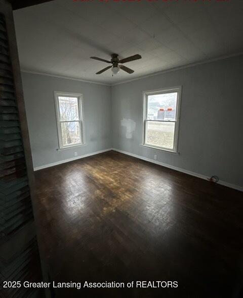 empty room with crown molding, dark wood-type flooring, and ceiling fan