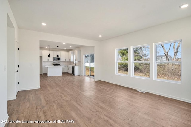 unfurnished living room with recessed lighting, visible vents, baseboards, and light wood finished floors