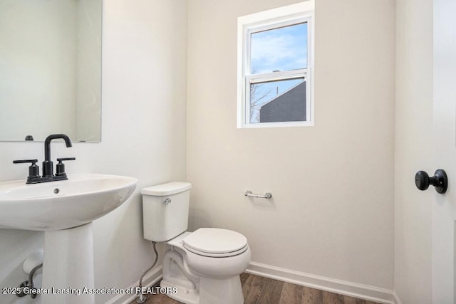 bathroom with a sink, baseboards, toilet, and wood finished floors