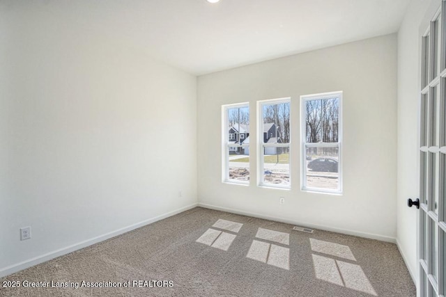 carpeted spare room featuring visible vents and baseboards