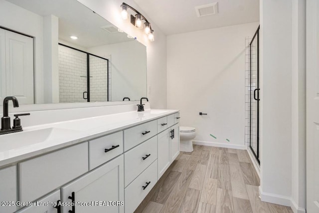 bathroom featuring a shower stall, double vanity, visible vents, and a sink