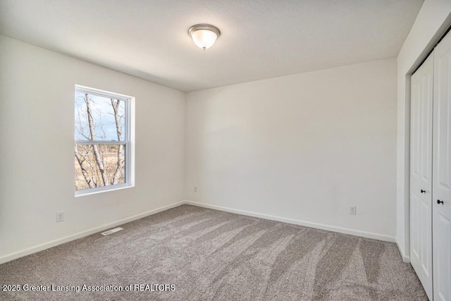 unfurnished bedroom with a closet, carpet floors, baseboards, and visible vents