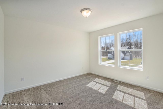 carpeted empty room featuring visible vents and baseboards