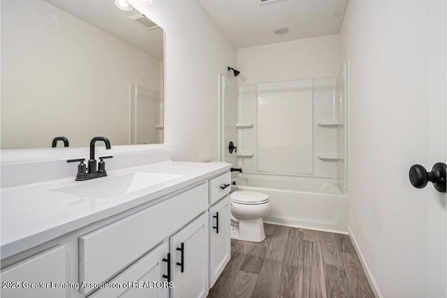 bathroom with baseboards, toilet, wood finished floors, vanity, and  shower combination