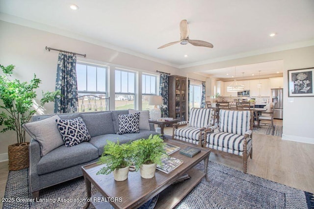 living area with baseboards, light wood finished floors, recessed lighting, ceiling fan, and crown molding