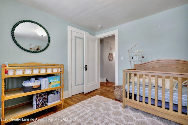 bedroom with light hardwood / wood-style flooring and a nursery area