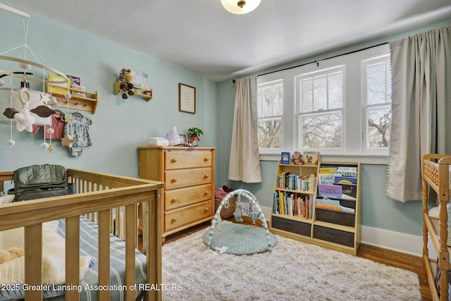 bedroom with hardwood / wood-style flooring and a crib