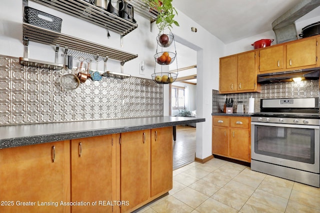 kitchen featuring tasteful backsplash, light tile patterned floors, stainless steel gas range oven, and range hood