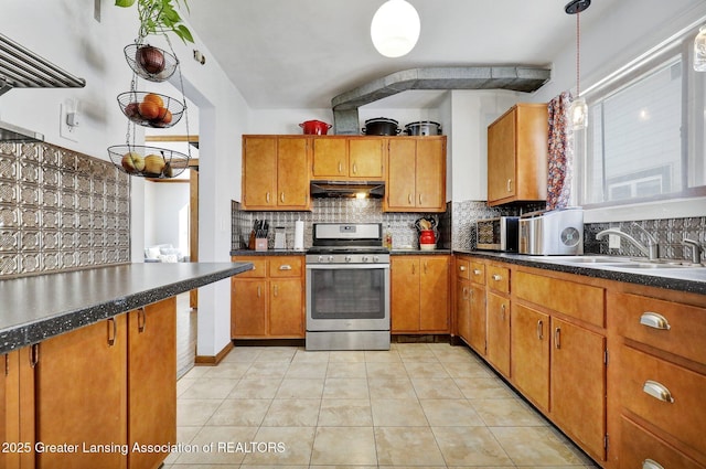 kitchen featuring sink, light tile patterned floors, stainless steel range with gas stovetop, pendant lighting, and backsplash