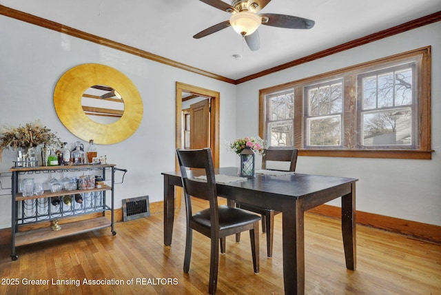 dining area with crown molding, ceiling fan, and light wood-type flooring