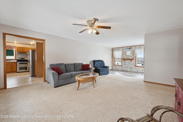 carpeted living room with ceiling fan and brick wall