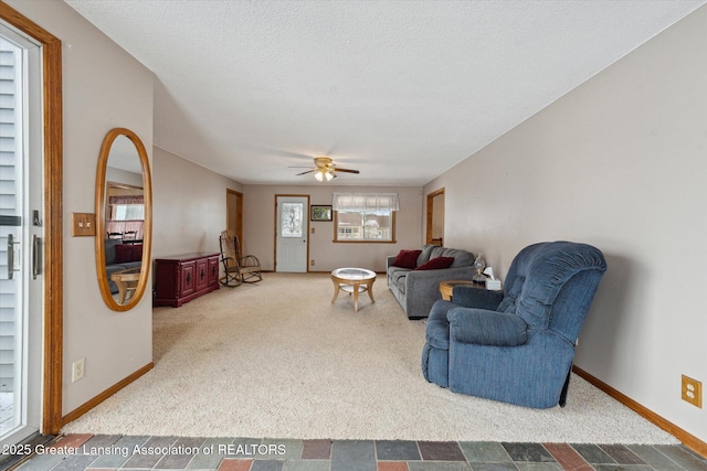 living room with a textured ceiling, ceiling fan, and carpet