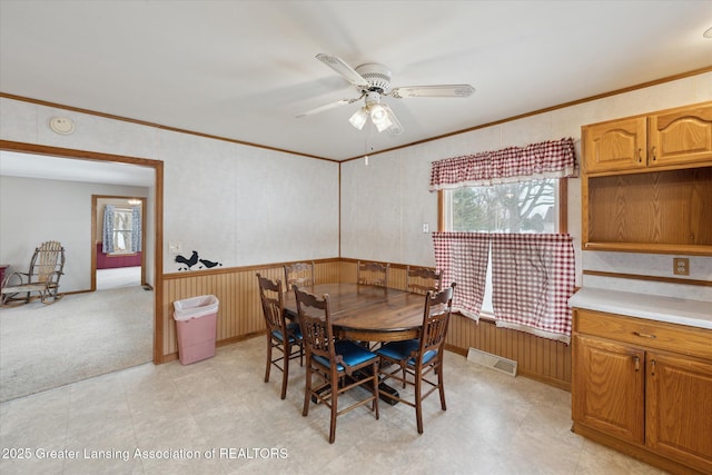 dining room featuring light colored carpet, ornamental molding, and ceiling fan