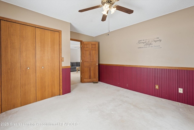 unfurnished bedroom with ceiling fan, light colored carpet, and a closet