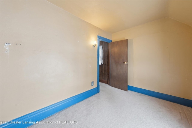 carpeted spare room featuring lofted ceiling