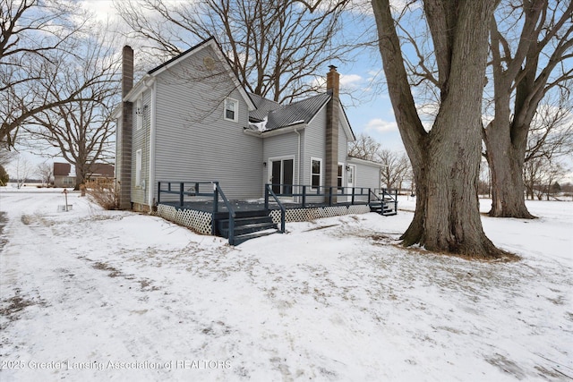 snow covered rear of property with a deck