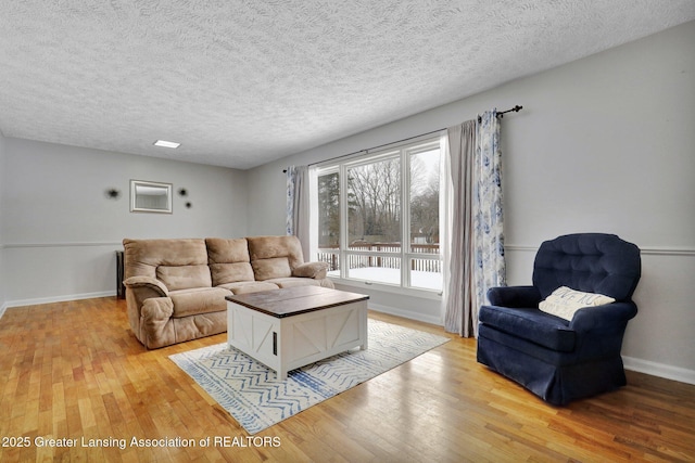 living room with a textured ceiling and light hardwood / wood-style flooring