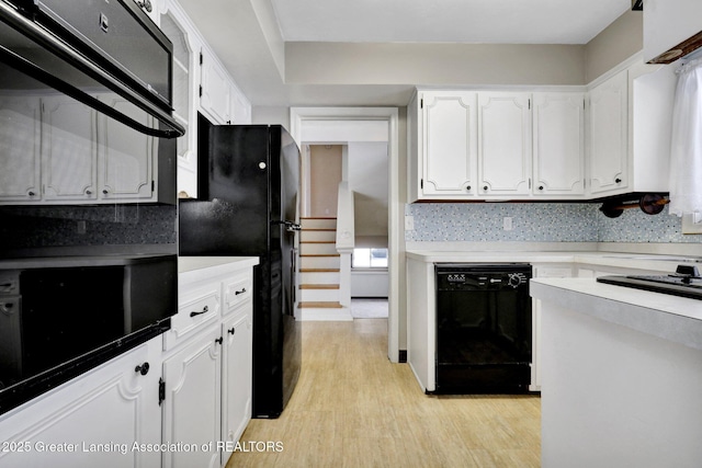 kitchen with white cabinetry, backsplash, light hardwood / wood-style flooring, and black appliances