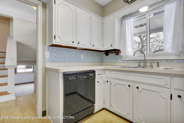 kitchen with white cabinetry, dishwasher, sink, decorative backsplash, and light hardwood / wood-style floors