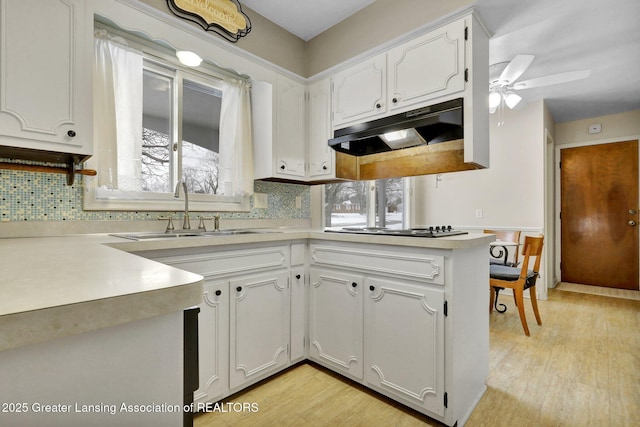 kitchen featuring gas cooktop, sink, white cabinets, and kitchen peninsula