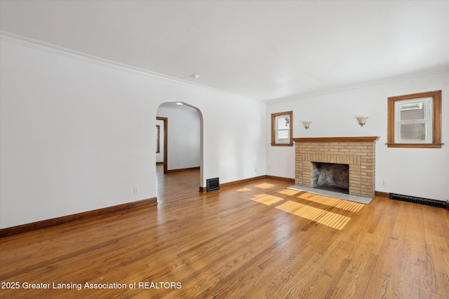 unfurnished living room with ornamental molding, a brick fireplace, and light hardwood / wood-style floors