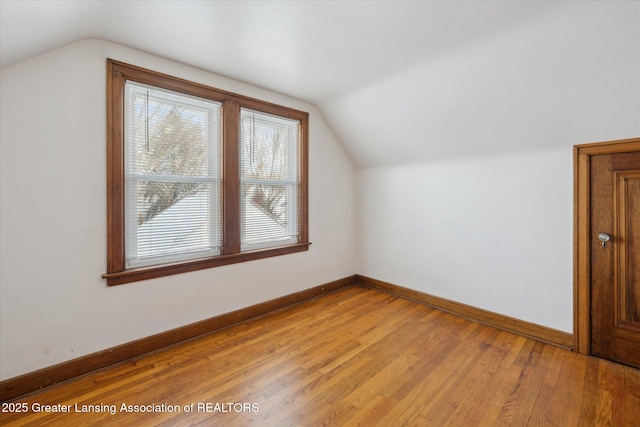 additional living space featuring vaulted ceiling and light hardwood / wood-style flooring