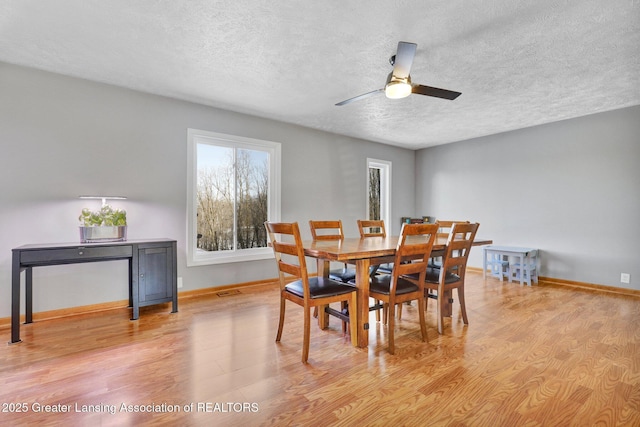 dining area with ceiling fan, light hardwood / wood-style flooring, and a textured ceiling