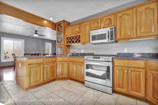 kitchen featuring stainless steel appliances, a textured ceiling, dark stone counters, and kitchen peninsula