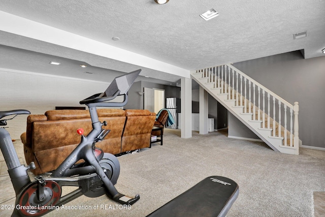 exercise room featuring light colored carpet and a textured ceiling