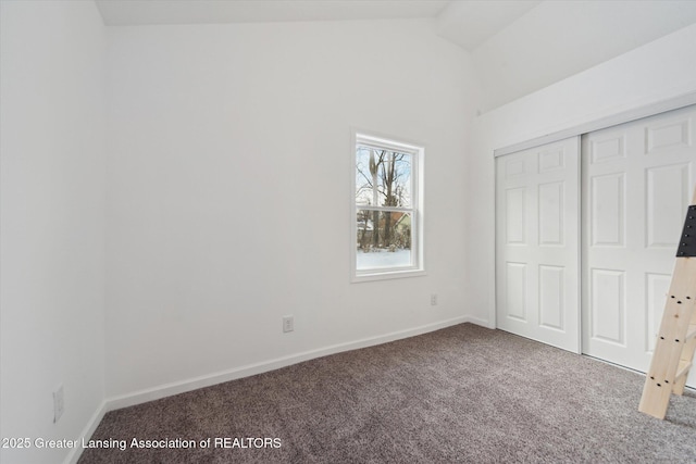 unfurnished bedroom featuring carpet floors, a closet, and vaulted ceiling