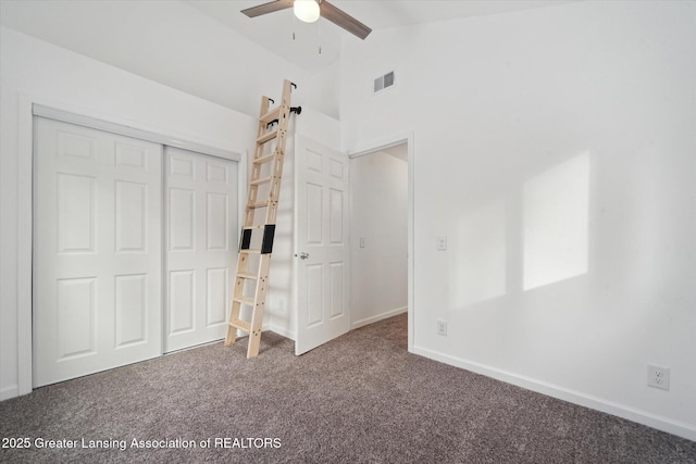 unfurnished bedroom featuring vaulted ceiling, carpet flooring, ceiling fan, a barn door, and a closet