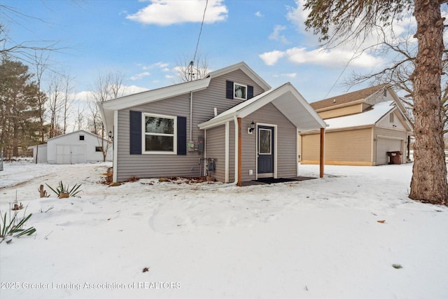 snow covered house featuring an outbuilding and a garage