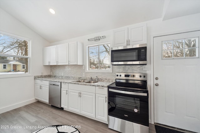 kitchen with stainless steel appliances, white cabinetry, sink, and decorative backsplash